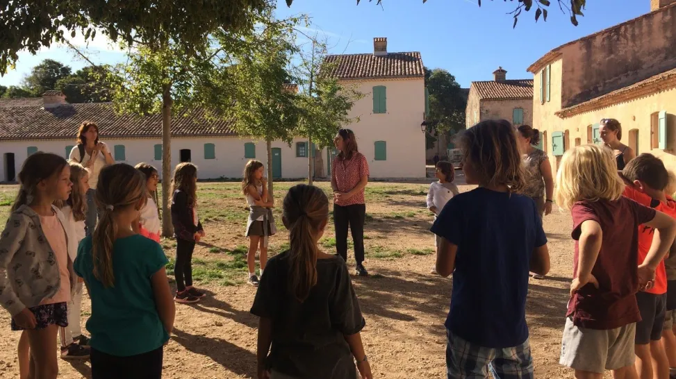 On peut voir des étudiants ainsi que des écoliers en rond. Ils font un atelier d'imagination.